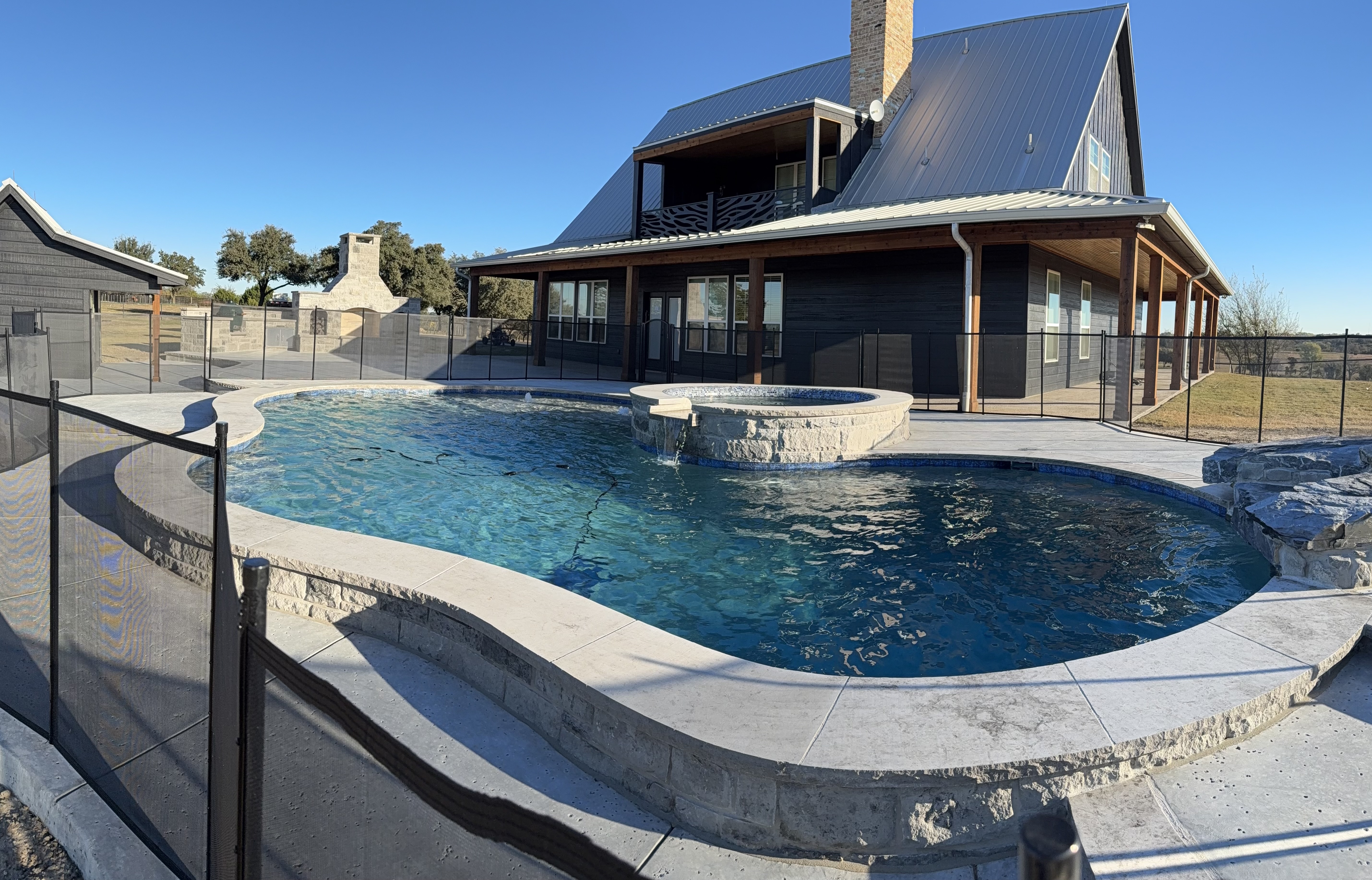 Free, form pool with elevated spa and modern farmhouse